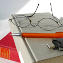 Brille, Stift und Buch